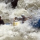 Action shot of a raft cresting a wave in the fast-moving Cheoah river, showcasing the excitement and adventure of rafting.