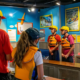 a vibrant indoor rafting instruction room, featuring a diverse group of adventurous tourists attentively engaging with an experienced guide as they review safety protocols and equipment for ocoee river rafting tours, under bright, focused lighting.