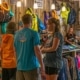 a vibrant, candid scene in a bustling outdoor adventure outfitter shop, showcasing families enthusiastically selecting rafting gear and maps while discussing essential preparation tips for their thrilling middle ocoee rafting trip.